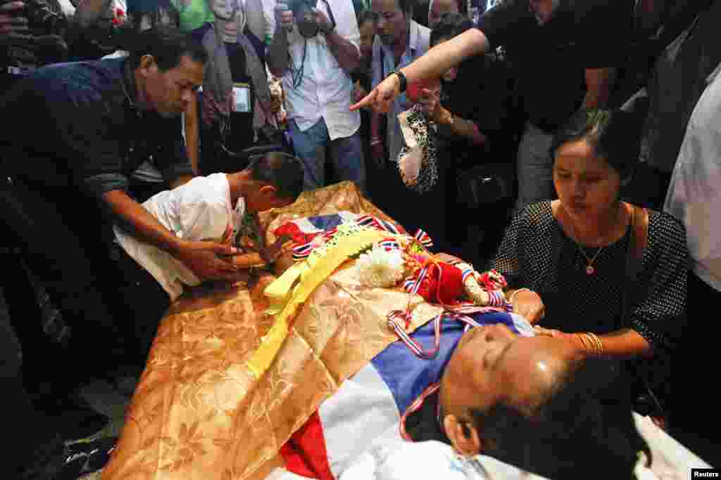 Prakrong Choochan, seen here at a Buddhist ceremony with his wife and son, was killed when a grenade was thrown at anti-government protesters, Bangkok, Thailand, Jan. 19, 2014.