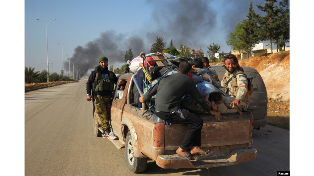 Rebel fighters ride a pick-up truck with civilians who fled areas of conflict in Dahiyet al-Assad, west Aleppo city, Syria, Oct. 30, 2016.
