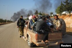 Rebel fighters ride a pick-up truck with civilians who fled areas of conflict in Dahiyet al-Assad, west Aleppo city, Syria, Oct. 30, 2016.