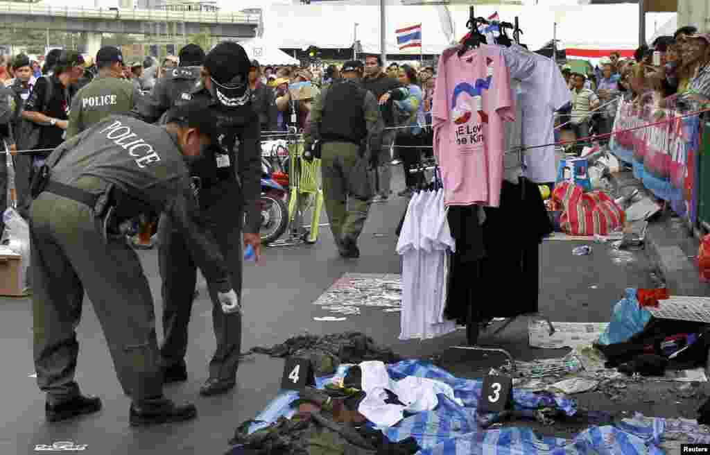 Police officers investigate the scene where an explosion took place near a camp of anti-government protesters at the Victory Monument in Bangkok, Jan. 19, 2014.