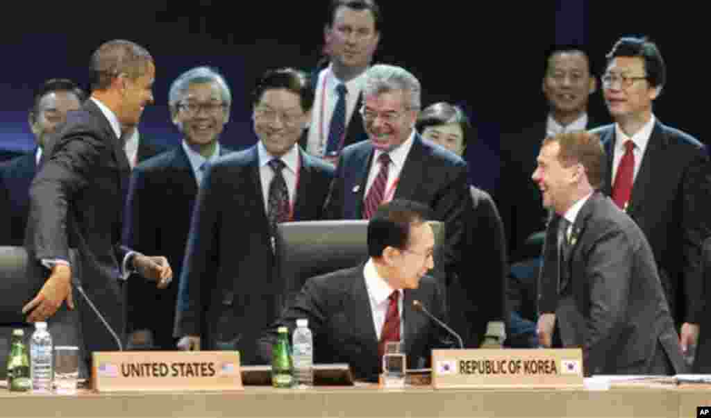 U.S. President Barack Obama, left, gets a reaction from Russian President Dmitry Medvedev, right, after jokingly covering up his microphone as they attend the opening plenary session at the Nuclear Security Summit at the Coex Center, in Seoul, South Korea