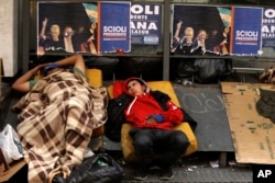 FILE - Homeless people rest downtown in Buenos Aires, Argentina, Oct. 21, 2015.