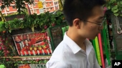 A man walks past a tricycle cart decorated with flowers and a poster with Chinese President Xi Jinping and other top leaders, parked on a street in Beijing, July 9, 2016. Overseas bar associations and lawyers groups have issued an open letter to Chinese P