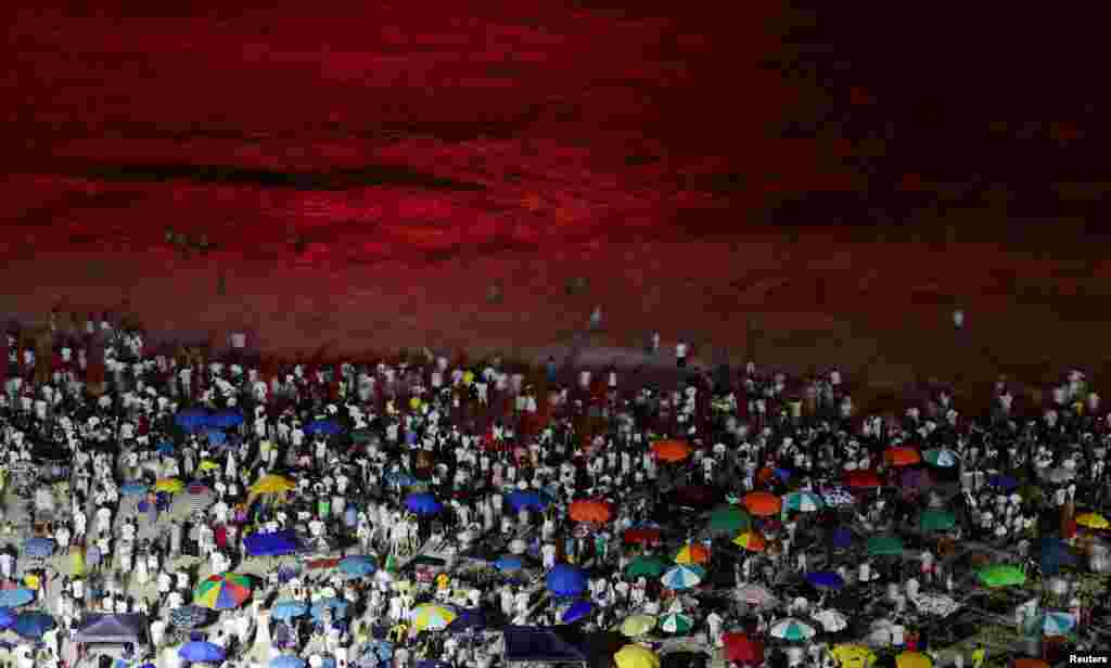 People watch as fireworks explode over Copacabana beach during New Year celebrations in Rio de Janeiro, Brazil, Jan. 1, 2022.