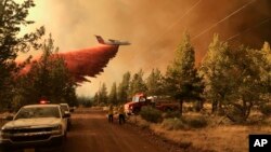 Pesawat pemadam kebakaran menebarkan zat pemadam api untuk memadamkan api kebakaran hutan di dekat Sisters, Oregon, Minggu 11 Juli 2021.