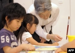 Permaisuri Michiko (kanan) berbincang dengan seorang anak perempuan sambil memperhatikan anak-nak lain menggambar di tempat penitipan anak di Kangaroom Shiodome, Tokyo, 15 Mei 2009.