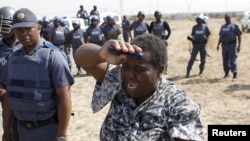 Uma mulher a chorar confronta os polícias que dispararam sobre os mineiros