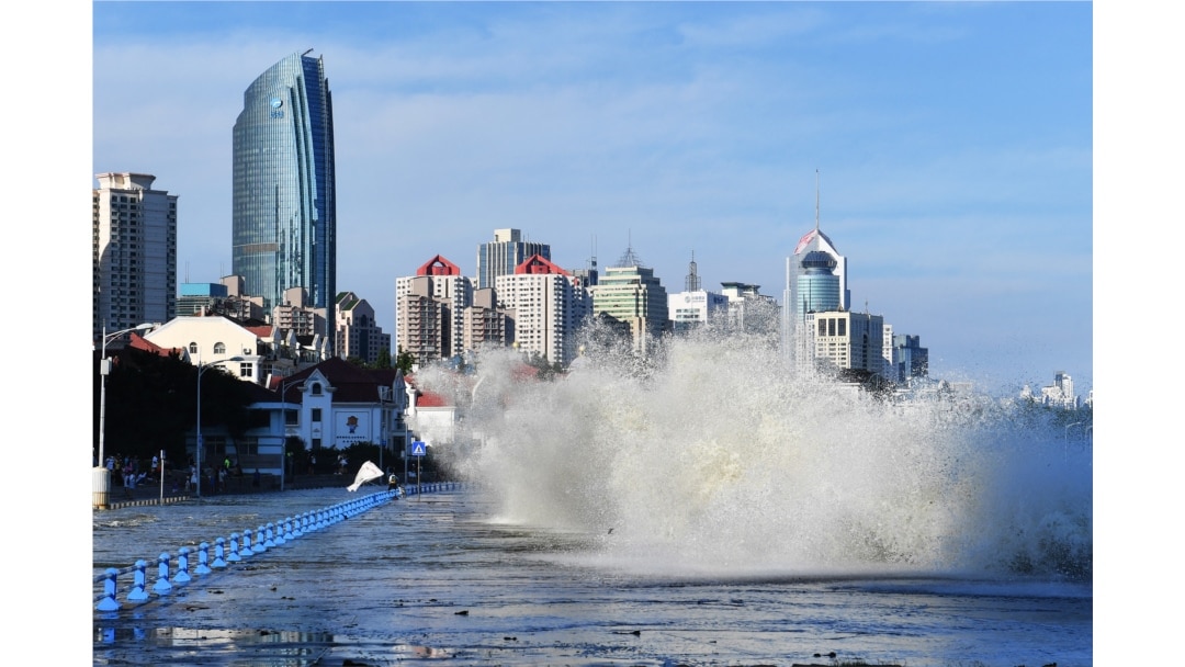 Gelombang yang disebabkan oleh Topan In-Fa, menghantam dan melewati penghalang di sepanjang pantai di Qingdao di provinsi Shandong timur China, 25 Juli 2021. (Foto: STR / AFP)