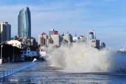 Gelombang yang disebabkan oleh Topan In-Fa, menghantam dan melewati penghalang di sepanjang pantai di Qingdao di provinsi Shandong timur China, 25 Juli 2021. (Foto: STR / AFP)