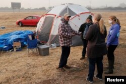 Randy Greb, who lost his house in Paradise in the Camp Fire, talks with employees of the Butte County Department of Employment and Social Services near his tent in a makeshift evacuation center in Chico, Calif., Nov. 16, 2018.