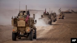 FILE - An American military convoy proceeds during a joint exercise with Syrian Democratic Forces at the countryside of Deir el-Zour in northeastern Syria, Dec. 8, 2021.