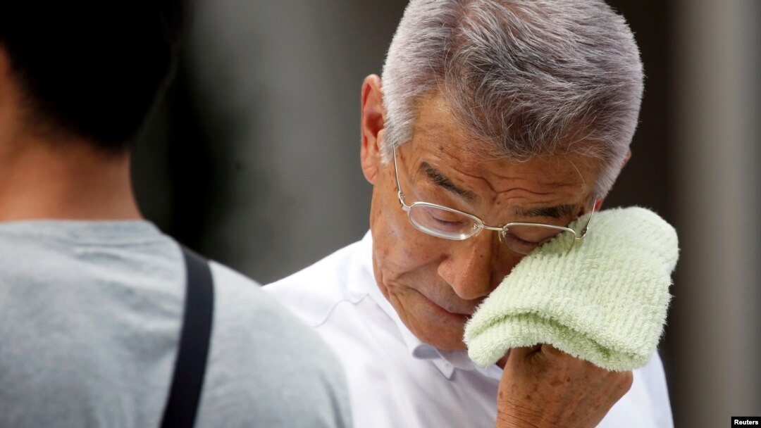 A businessman wipes his face while walking on a street during a heatwave in Tokyo, July 23, 2018.
