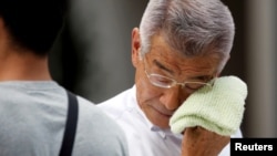 A businessman wipes his face while walking on a street during a heatwave in Tokyo, July 23, 2018.