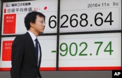 A man walks by an electronic stock board of a securities firm in Tokyo, Nov. 9, 2016.