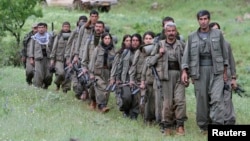 Kurdistan Workers Party (PKK) fighters walk on the way to their new base in northern Iraq May 14, 2013. The first group of Kurdish militants to withdraw from Turkey under a peace process entered northern Iraq on Tuesday, and were greeted by comrades from 