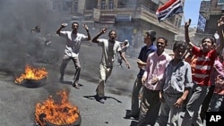 Anti-government protesters chant slogans next to burning tires during a demonstration demanding the resignation of Yemeni President Ali Abdullah Saleh in Taiz, Yemen, April 18, 2011