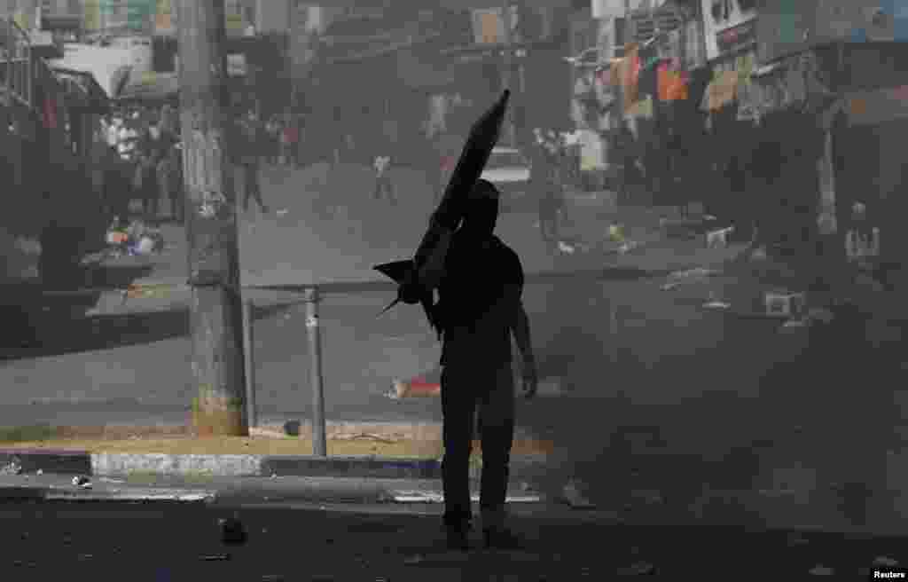 A protester holds a mock rocket during a demonstration against the Israeli offensive in Gaza, in the West Bank city of Hebron, Aug. 22, 2014.