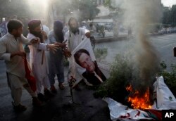 FILE - Supporters of Pakistani radical groups burn a poster of Pakistani Prime Minister Imran Khan during a rally to condemn a Supreme Court decision that acquitted Asia Bibi, a Christian woman, who spent eight years on death row accused of blasphemy, in