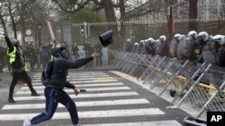 Un manifestante arroja un objeto a la fila de la policía durante una manifestación en Bruselas, el sábado 8 de diciembre. (Foto: AP)