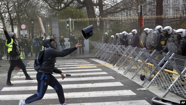 Un manifestante arroja un objeto a la fila de la policía durante una manifestación en Bruselas, el sábado 8 de diciembre. (Foto: AP)