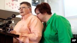 Jayne Rowse (L) speaks as partner April DeBoer kisses her during a news conference in Ferndale, Michigan, March 21, 2014.