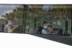 Mahasiswa asing melambaikan tangan mereka dari bus setibanya di Bandara Darwin, Australia, 30 November 2020.