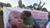 Une partisane de Laurent Gbagbo embrasse son portrait à Abidjan le 31 août 2020, lors du dépôt de son dossier de candidature à la commission électorale. (Photo by SIA KAMBOU / AFP)