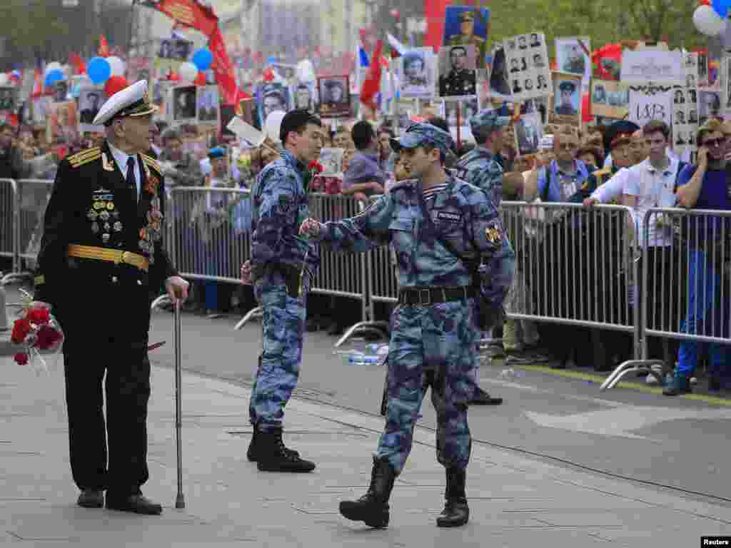 A member of Russia&#39;s National Guard presents flowers to a veteran during celebrations of Victory Day, which marks the anniversary of the victory over Nazi Germany, Moscow, May 9, 2019.