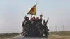 FILE - U.S.-backed Syrian Democratic Forces fighters stand on their pickup as the flash victory signs after battling the Islamic State militants, northeast Syria, July 26, 2017.