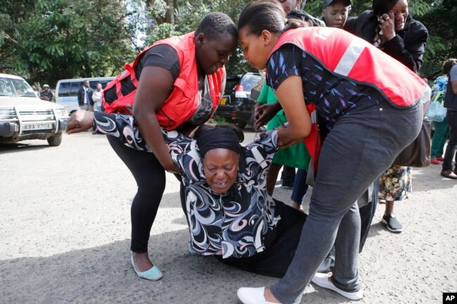 Kenya Red Cross personnel helps a woman reacting after learning of a family member killed during a recent terrorist attack Wednesday, Jan. 16 2019, at the Chiromo Mortuary, Nairobi, Kenya.