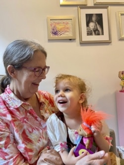 Mary Pupko sits with her granddaughter Evelyn. Pupko, a 64-year-old retired seamstress with multiple sclerosis, moved to Brooklyn from Seattle to be closer to her family. (Elisa Pupko via AP)