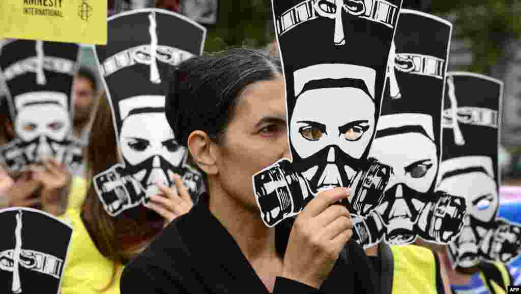 Selim Caliskan, Germany head of human rights organisation Amnesty International, and other activists hold up masks of Nefertiti, the wife of Egyptian Pharaoh Akhenaten, and posters reading &quot;Egypt: Stop Further Bloodshed!&quot; as they demonstrate against violence in Egypt, in front of the Egyptian embassy in Berlin.