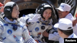 FILE - Liu Yang, center, China's first female astronaut, waves next to her comrade Jing Haipeng, in this June 29, 2012 photo.