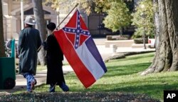 FILE -A couple leaves the grounds of the state Capitol in Jackson, Miss., after participating in a rally in support of keeping the Confederate battle emblem on the state flag, Jan. 19, 2016.