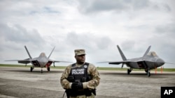 A member of the U.S. military police stands in front of U.S. Air Force F-22 Raptor fighter jets that were flown April 25, 2016, to the Mihail Kogalniceanu air base in southeast Romania, as a show of support to deter Russian aggression in the region.