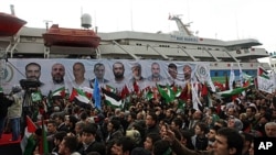 People, holding Turkish and Palestinian flags, cheer as the Mavi Marmara ship, in the background, the lead boat of a flotilla headed to the Gaza Strip which was stormed by Israeli naval commandos in a predawn confrontation in the Mediterranean May 31, 201