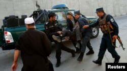 Des policiers afghans transportent un blessé après une explosion à Kaboul, le 31 octobre 2017.