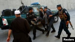 Afghan policemen carry an injured man after a blast in Kabul, Afghanistan, Oct. 31, 2017. 