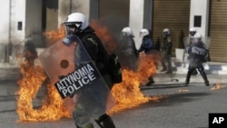 Riot policemen dodge petrol bombs thrown by protesters during a rally in Athens, Nov. 12, 2015. Clashes have broken out as the country faces its first general strike since the Greece's left-led government came to power in January.