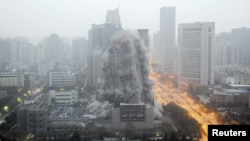 FILE - A building crumbles during a controlled demolition to make way for a new commercial center in Xi'an, Shaanxi province, China.