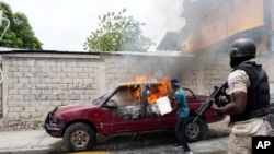 Un trabajador intenta apagar un vehículo en llamas que pertenece a Radio Tele-Ginen durante una protesta que exige la renuncia del presidente Jovenel Moise en Puerto Príncipe, Haití, el lunes 10 de junio de 2019.