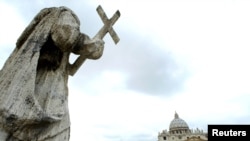 A marble statue of St. Peter overlooks the Vatican Basilica in St. Peter's Square.