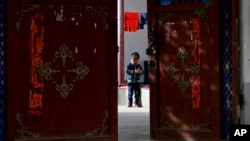 In this Sept. 20, 2018, file photo, an Uighur child plays alone in the courtyard of a home at the Unity New Village in Hotan, in western China's Xinjiang region.