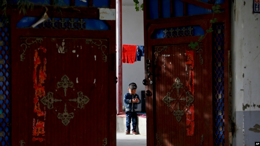 资料图：新疆和田的一名维吾尔小孩独自在家中院子里玩耍 （美联社 2018年9月20日）