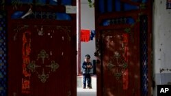 资料图：新疆和田的一名维吾尔小孩独自在家中院子里玩耍 （美联社 2018年9月20日）