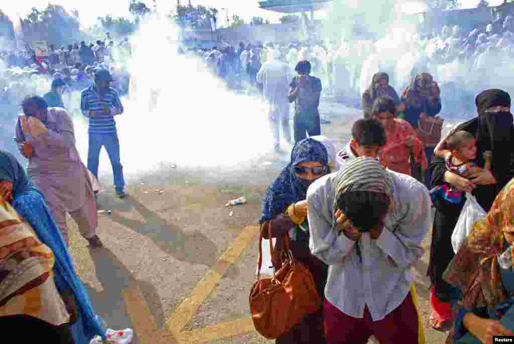Supporters of cleric Tahir-ul-Qadri run away from tear gas during clashes with police outside the airport in Rawalpindi, Pakistan, June 23, 2014.