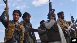 Afghan militia men raise their weapons as they stand guard in the Achin district of Nangarhar province east of Kabul, Afghanistan, Dec. 27, 2015.