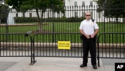 FILE - A member of the United States Secret Service Uniformed Division looks out over Pennsylvania Avenue as he stands in front of a temporary barrier in front of the White House in Washington, Oct. 3, 2014.