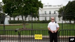 一位穿制服的特勤人员站在白宫围栏外面，看着宾夕法尼亚大道（2014年9月22日）
