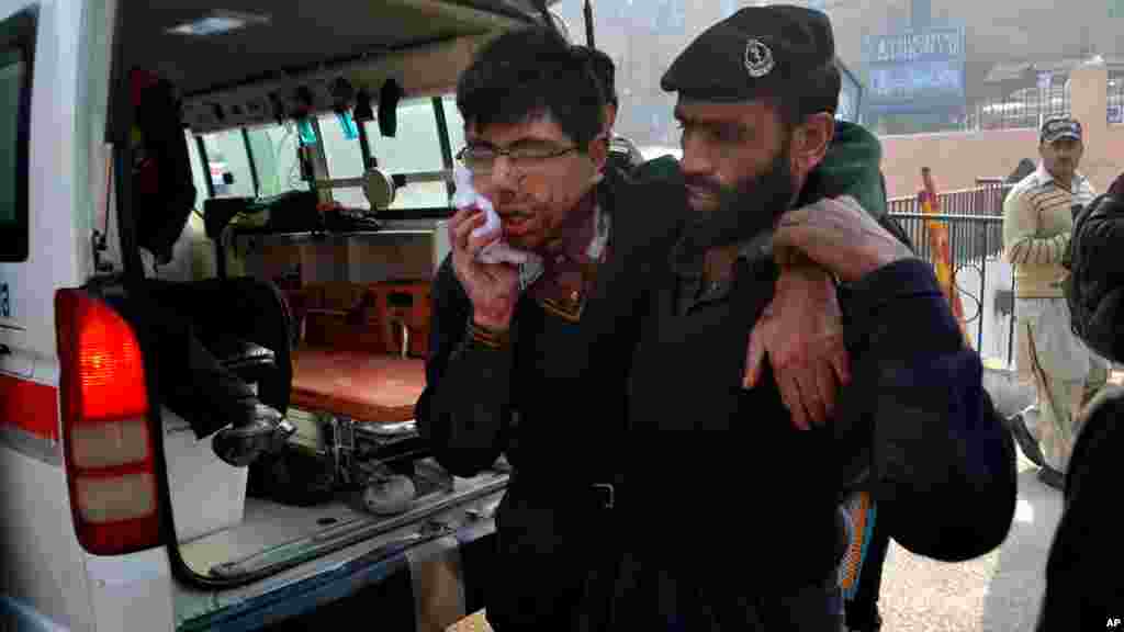 Un garde de sécurité de l&#39;hôpital aide un étudiant blessé dans la fusillade dans une école sous l&#39;attaque par des hommes armés talibans à Peshawar, au Pakistan, le mardi 16 décembre 2014.